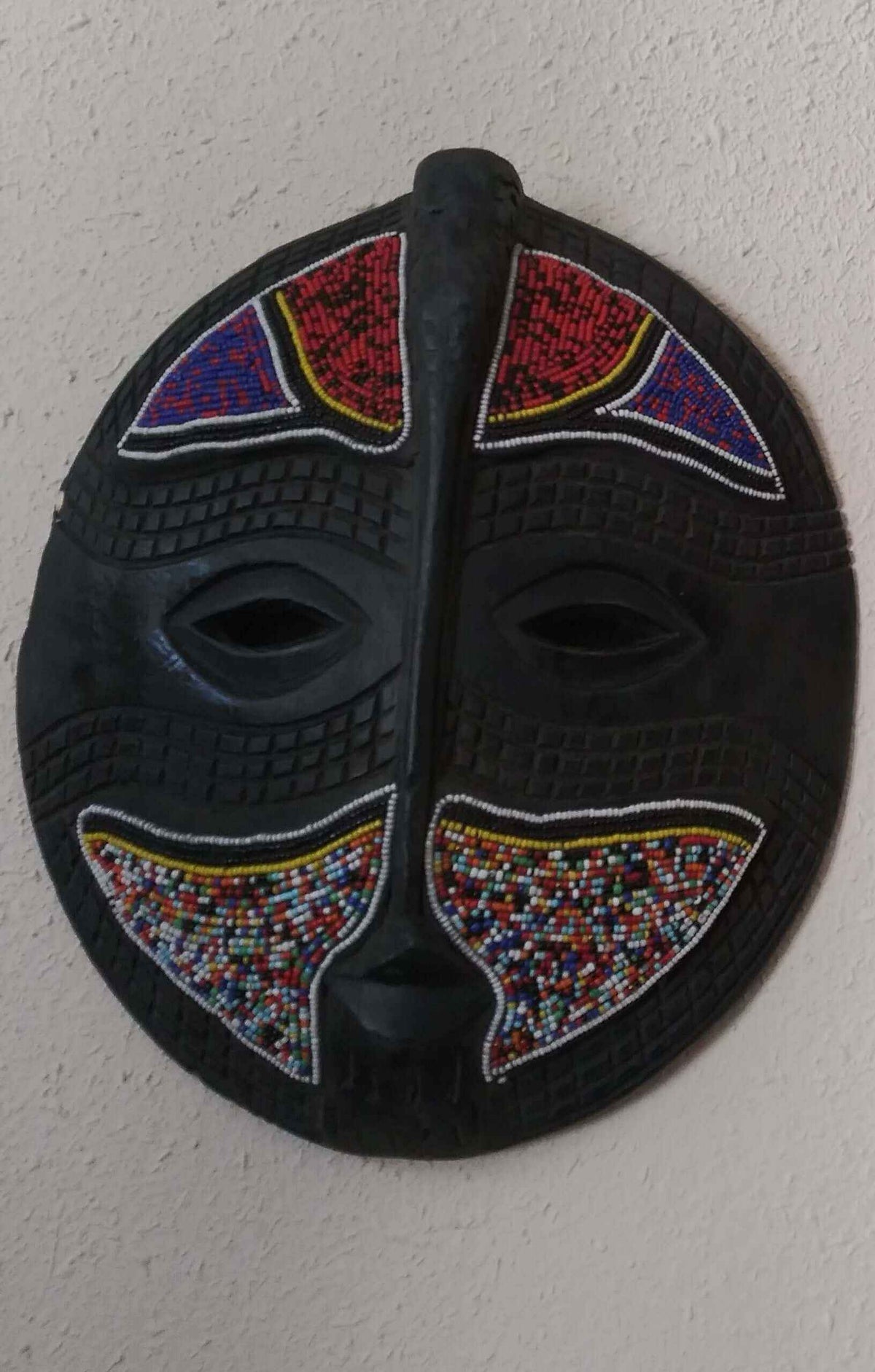 Round colorful wall mask with intricate patterns and vibrant colors for decorative wall art